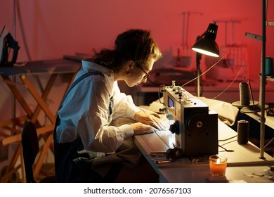 Fashion designer sew clothing. Young woman busy working on sewing machine in studio. Self-employed tailor preparing for new clothes collection presentation in workshop showroom. Small business concept - Powered by Shutterstock