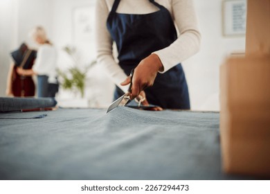 Fashion designer and tailor cutting fabric and making or preparing pattern for stylish, trendy and fashionable clothes. Workshop or boutique seamstress using denim material or textile for edgy wear - Powered by Shutterstock