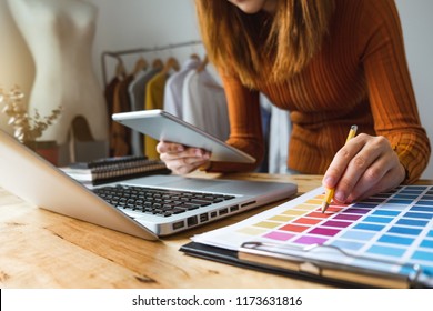 Fashion Designer Talking Mobile Phone And Using Laptop With Digital Tablet Computer In Modern Studio