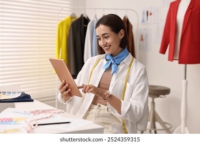 Fashion designer using tablet at table in workshop - Powered by Shutterstock