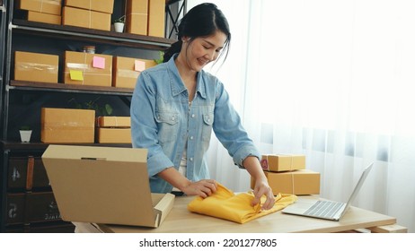 Fashion designer Women packing box on table checking goods quality package. Asian women startup small business at home office desk pack fashion design clothing. Asian woman packing startup business