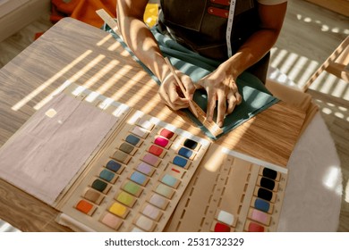 a fashion designer is working in his studio doing what he loves, he does many things such as using a sewing machine to sew a dress, choosing the fabric to use to make the dress - Powered by Shutterstock