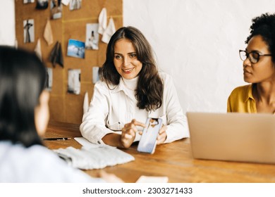 Fashion designers collaborate with a client in an office, discussing and presenting designs for a new fashion line. Business women working together to bring their creative vision to life. - Powered by Shutterstock