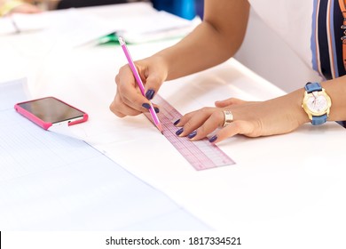 Fashion designer's hands. Closeup of hands drafting a new sewing pattern on paper, working on blueprint plans with a pencil, a ruler, smartphone, tools. Industry, hobby, workspace. Creation process - Powered by Shutterstock