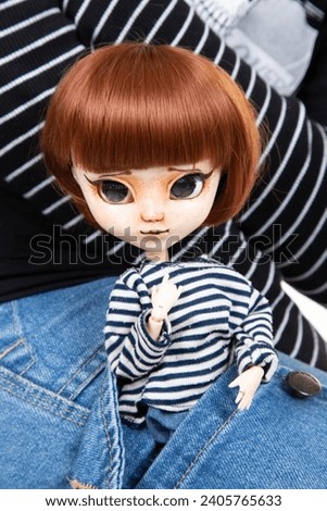 fashion doll with scary look in white and black sailor sweater in the girl jeans pocket