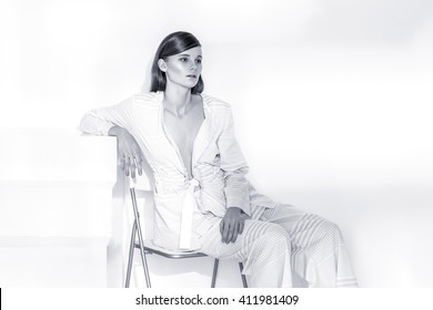 Fashion editorial shot in studio with white background. Beautiful model posing in total white clothes.