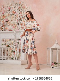 Fashion Female Model In White Sun Dress With Floral Print Standing And Posing In Pink Room