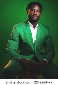 Fashion, formal and black man in a green suit sitting on a chair in studio with a luxury outfit. Elegant, stylish and portrait of an African male model with fashionable clothes isolated by background - Shutterstock ID 2249264497