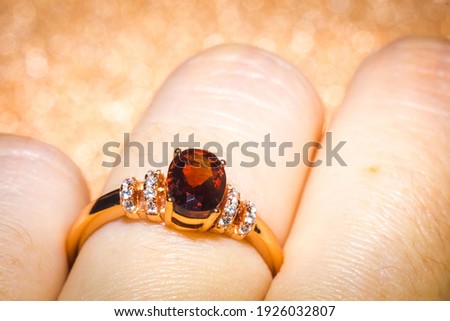 Fashion golden ring with a dark red garnet stone.