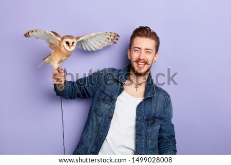 fashion guy laughing at his bird. happiness, friendship concept. close up portrait. studio shot. positive feeling and emotion