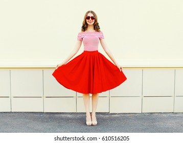 Fashion happy young smiling woman shows a red skirt over white city background 