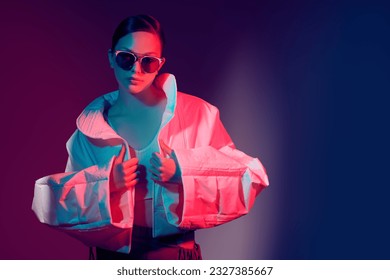 Fashion and haute couture style. Beautiful fashion model girl posing in stylish clothes with wide oversized shapes. Studio shot against a dark background in mixed color light. Bright colors. 