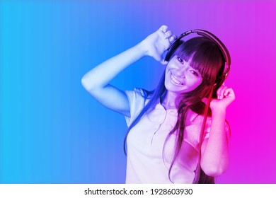 Fashion Hipster Girl Smiles And Wear Headphones Listening To Music Over Neon Background