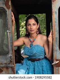 Fashion Image Of Beautiful Asian Indian Woman Wearing Blue Gown In A Junk Yard. 