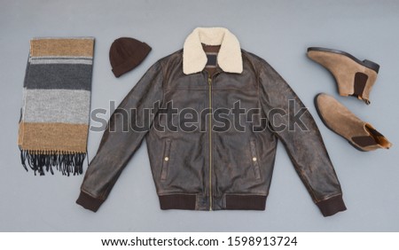 Fashion leather jacket with brown boots shoes, ,scarf ,hat isolated on gray background
