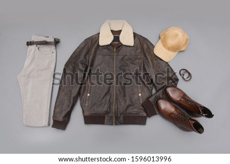 Fashion leather jacket with khaki pants and brown boots shoes,hat isolated on gray background
