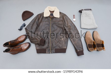 Fashion leather jacket with khaki pants and brown boots shoes,hat,sunglasses, watch  isolated on gray background
