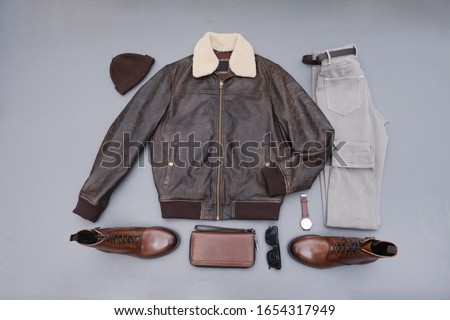 Fashion leather jacket with khaki pants and brown boots shoes,hat isolated on gray background
