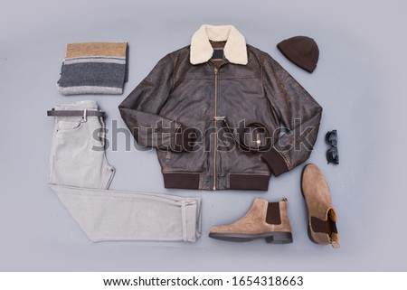 Fashion leather jacket with khaki pants and brown boots shoes,hat ,sunglasses isolated on gray background
