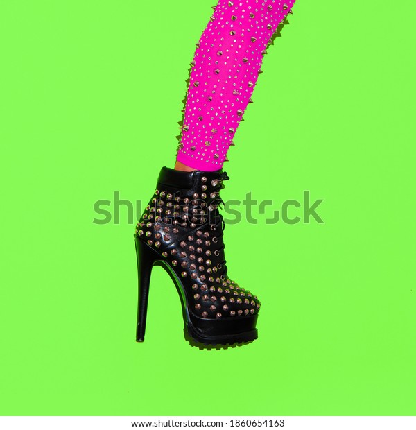 Fashion leg in heel\
party boots on green minimal background. Stylish clubbing mood.\
After party concept