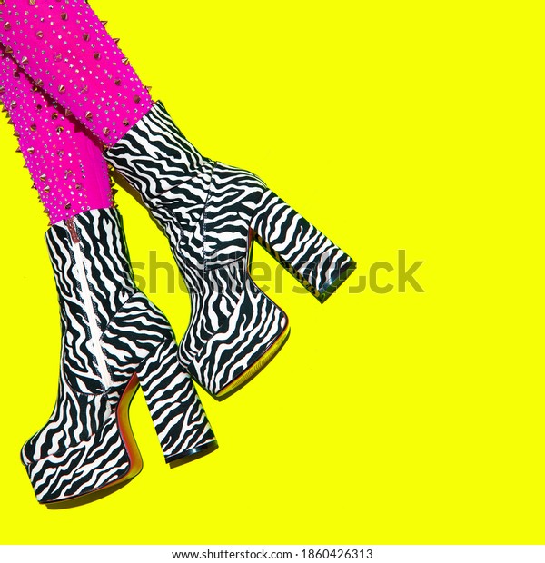 Fashion legs in heel party zebra print boots on\
yellow minimal background. Stylish clubbing mood.  Go-go Girls.\
Cabaret. After party\
concept