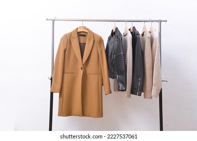 abrigo marrón largo de moda, suéter marrón con chaqueta negra en la percha