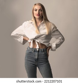 Fashion And Make-up Concept. Beautiful Long Hair Blonde Woman With Classic Outfit And Red Lipstick Studio Portrait. Slim Model Wearing Blue Jeans And White Blouse. Toned Image With Brown Color