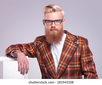 Fashion Man With Long Red Beard And Glasses Resting In Studio Looking At The Camera