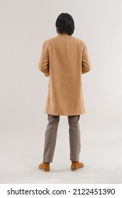 Fashion Model. Back View Young Man With Hairstyle In Coat Posing In Studio 

