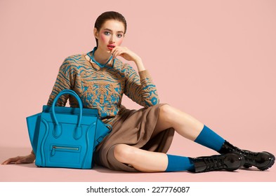 Fashion Model In Design Clothes And Blue Bag Posed On Light Color Background