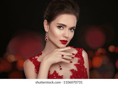 Fashion Model Diamond Jewelry. Beautiful Young Woman With Makeup, Expensive Earrings, Rings And Necklaces. Elegant Lady In Red Dress Showing Luxurious Jewellery Set. Beauty Makeup Portrait. 