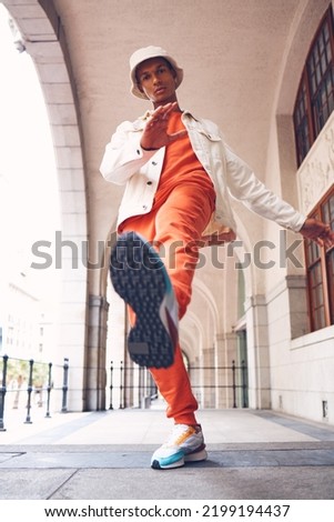 Fashion, model and gen z man from Spain with neon, trendy and luxury brand clothes. Clothing brand and leg kick pose of a hipster Spanish person with sports shoes posing by a building outdoors