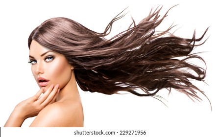 Fashion Model Girl Portrait with Long Blowing Hair. Glamour Beautiful Woman with Healthy and Beauty Brown Hair isolated on white background touching her face. Skin care and beautiful hair concept