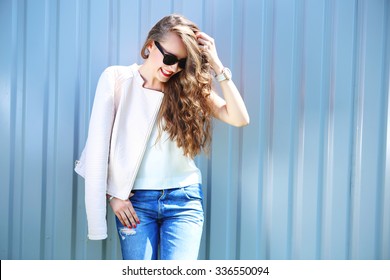 Fashion Model With Long Curly Hair Wearing Sunglasses Posing Outdoor. Jeans, Leather Jacket.