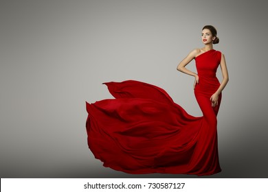 Fashion Model in Red Beauty Dress, Sexy Woman posing evening Gown, Flying Silk Tail over gray background