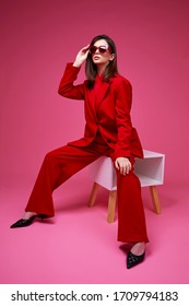 Fashion Model In Red Suit And Sunglasses. Studio Shot.