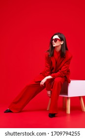 Fashion Model In Red Suit And Sunglasses. Studio Shot.