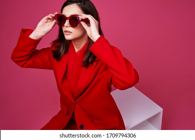 Fashion Model In Red Suit And Sunglasses. Studio Shot.