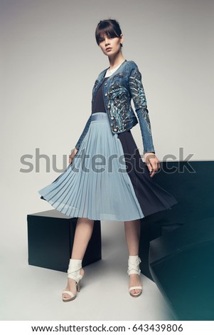 Fashion model in a stylish skirt and jacket posing in the studio