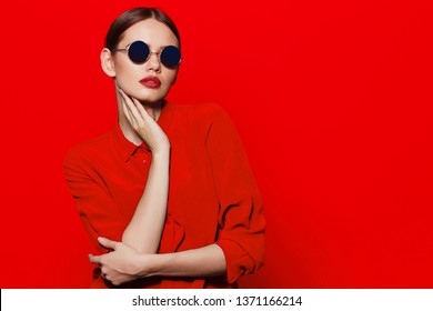 Fashion Model In Sunglasses, Beautiful Young Woman. Red Blouse, Red Background