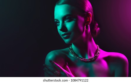 Fashion Model Woman In Colorful Bright Lights With Trendy Makeup . Beautiful Girl With Set Jewelry .   Woman In A Necklace With A Ring, Earrings And A Bracelet. Beauty And Accessories.