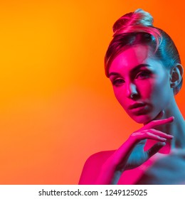 Fashion model woman in colorful bright lights posing in studio, portrait of beautiful sexy woman