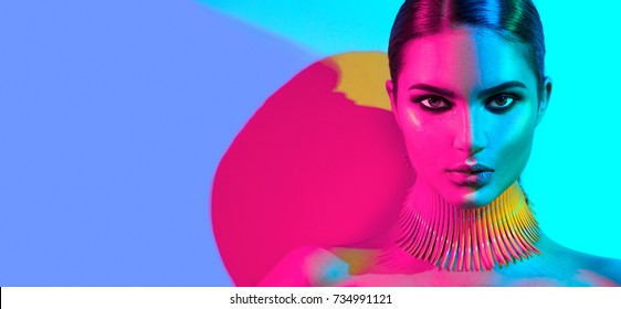 Fashion model woman in colorful bright lights posing, portrait of beautiful sexy girl with trendy make-up. Art design, colorful make up. Over colourful vivid background. Night club dancer