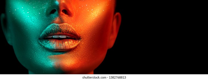 Fashion model woman skin face in bright sparkles, colorful neon lights, beautiful sexy girl lips, mouth. Trendy glowing gold skin make-up. Art design make up. Glitter metallic shine makeup