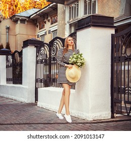 Fashion model woman wearing summer dress posing near old building gates - Shutterstock ID 2091013147