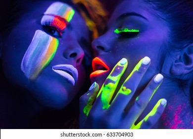 fashion models  in uv neon light with fluorescent glowing Body Art make-up . Low key dark image. Soft focus image.