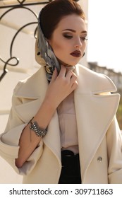 Fashion Outdoor Photo Of Beautiful Lady With Dark Hair Wearing Elegant Coat And Silk Scarf On Head,posing In Autumn Park 