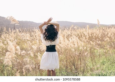fashion outdoor photo of beautiful woman with dark hair in elegant clothes posing in spring field with reeds Stock Photo