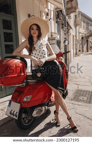 fashion outdoor photo of beautiful woman with dark hair in elegant dress with accessories posing on motorbike
