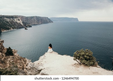 아름다운 자연을 배경으로 포즈를 취하고 있는 우아한 웨딩드레스를 입은 멋진 신부의 멋진 야외 사진, 바다와 산들이 배경에 있다 스톡 사진